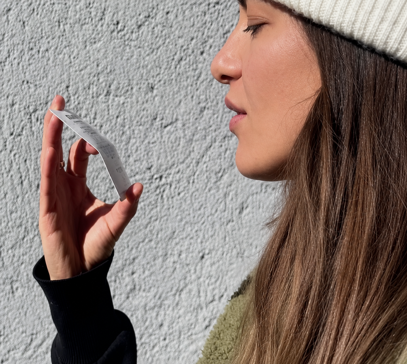 Woman holding a small rectangular object against a light gray wall